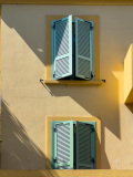 Fenêtres vertes pâles aux volets fermés sur une façade jaune
