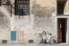 Bicyclette blanche accolée à un mur décrépi et délavé, Flo