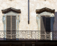 Deux fenêtres symétriques avec volets de bois sur un balcon en