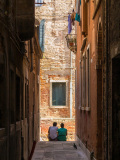 Un couple se repose sur les marches au bord d'un canal de Venise